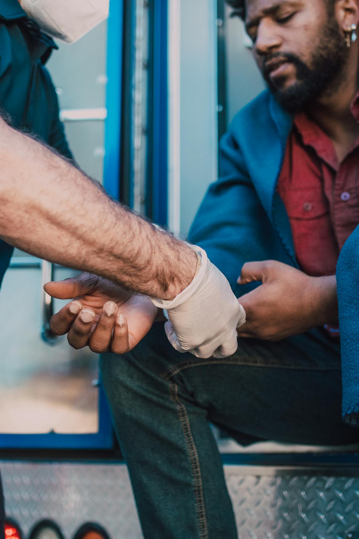 A paramedic gives first aid to an injured man sitting in an ambulance, emphasizing emergency care.